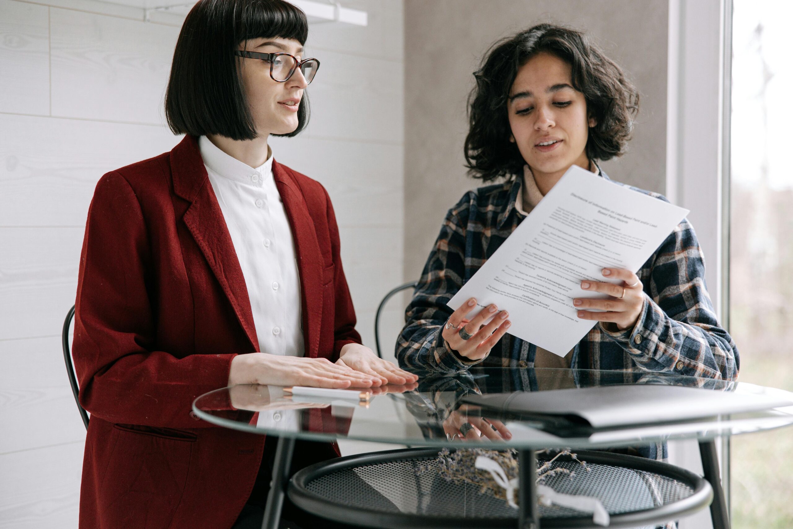 Two women reviewing real estate documents, indicating a decision or agreement indoors.